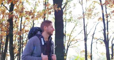 年轻的旅游走背包秋天森林阳光明媚的一天高加索人的家伙微笑相机